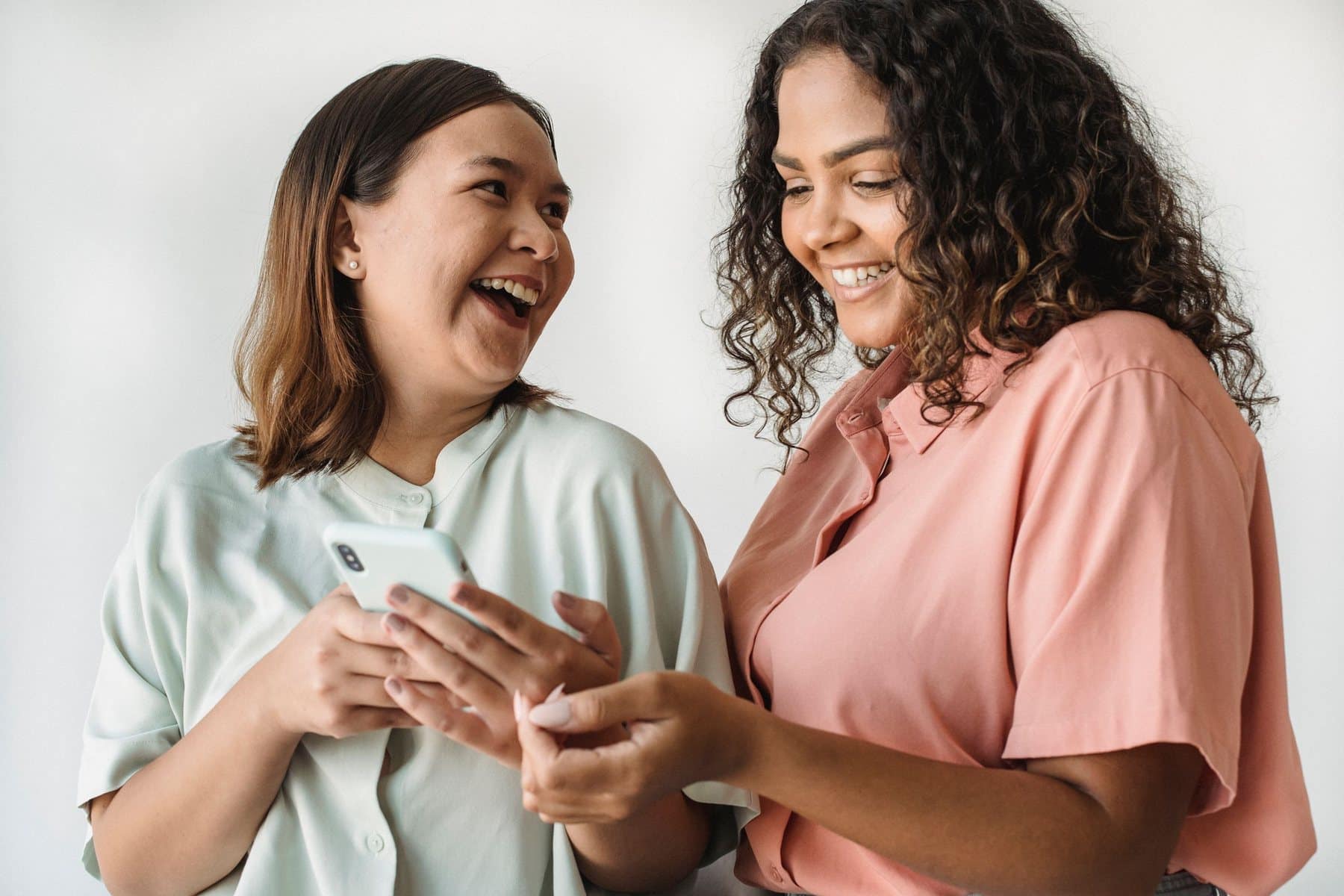 Duas amigas a rir enquanto veem algo no telemóvel